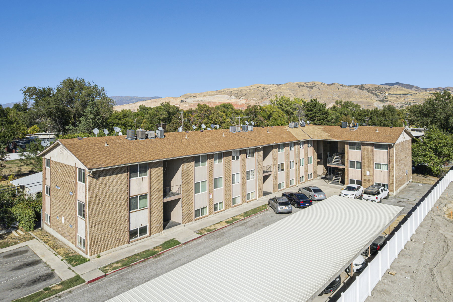 Multi-story building featuring brick and siding exterior, brown shingle roofing, and multiple windows
