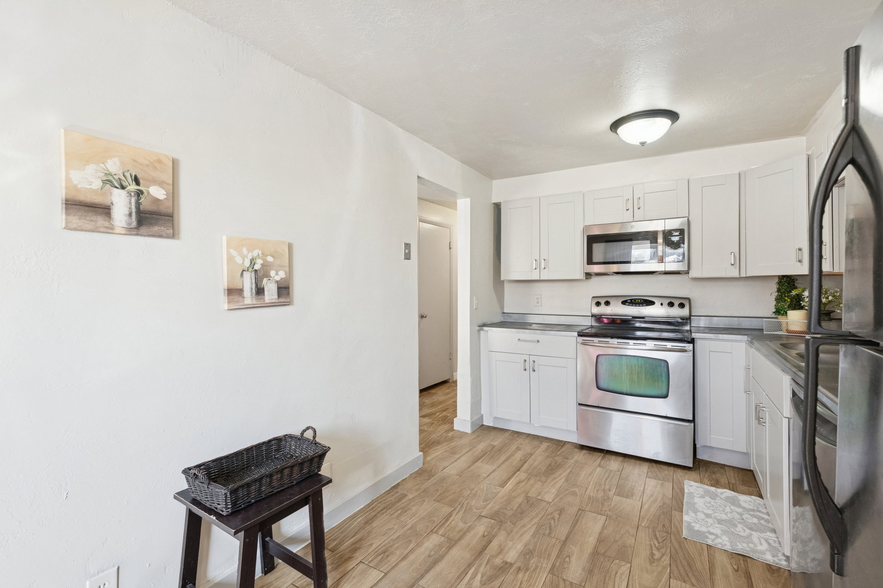 Well-appointed kitchen featuring light-toned cabinetry, stainless steel appliances, dark countertops, and wood-finish flooring