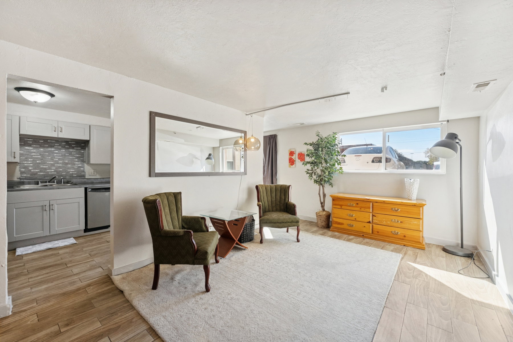 Open concept living area with wood-finish flooring, a neutral color palette, and a large window providing natural light
