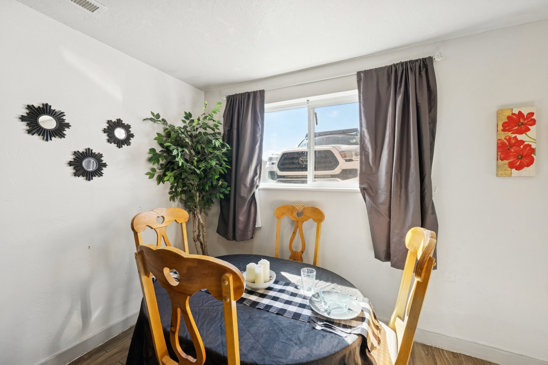Dining area featuring wood-finish flooring, a window with curtains, and white walls