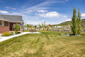 Spacious green lawn featuring a covered wood deck, concrete patio area, and decorative rock landscaping