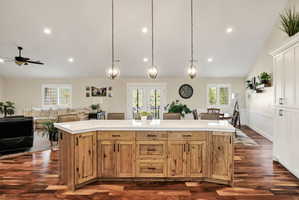 Spacious open concept living area featuring a large wood-finish kitchen island with a light-toned countertop, recessed lighting, and wood-finish flooring