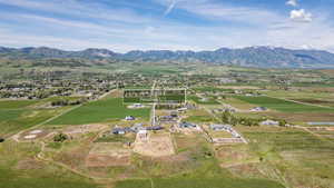 Expansive aerial perspective showcasing a rural landscape with scattered residences, agricultural fields, and a prominent mountain range in the background
