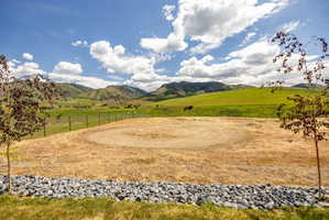 Expansive land parcel featuring a circular clearing, perimeter fencing, and distant mountain ranges