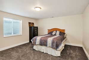 Carpeted room featuring a window with blinds, a ceiling-mounted light fixture, and light-toned walls with white baseboards