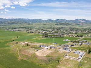Expansive green fields with distant mountain ranges under a blue sky with scattered clouds