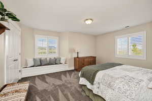 Spacious room featuring a built-in window seat, two windows with plantation shutters, neutral wall paint, and patterned carpet flooring