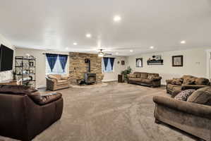 Spacious room with a stone-clad accent wall, a freestanding wood stove, recessed lighting, and a ceiling fan