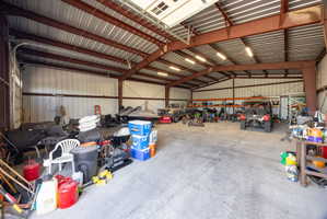 Spacious metal building with a concrete floor, exposed steel beam construction, corrugated metal walls, and overhead lighting