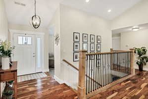 Entryway featuring rich wood-finish flooring, a white paneled door with sidelight, and an overhead orb chandelier