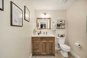 Bathroom featuring a natural wood-finish vanity with a white countertop and undermount sink, a framed mirror, and a two-light fixture