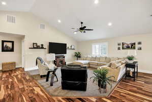 Expansive living area featuring vaulted ceilings, recessed lighting, and rich wood-finish flooring
