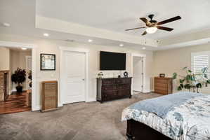 Carpeted room featuring a ceiling fan with integrated lighting, recessed lighting, and a tray ceiling