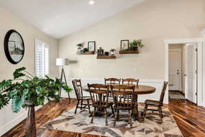 Vaulted ceiling with recessed lighting, wood-finish flooring, white plantation shutters, and wainscoting