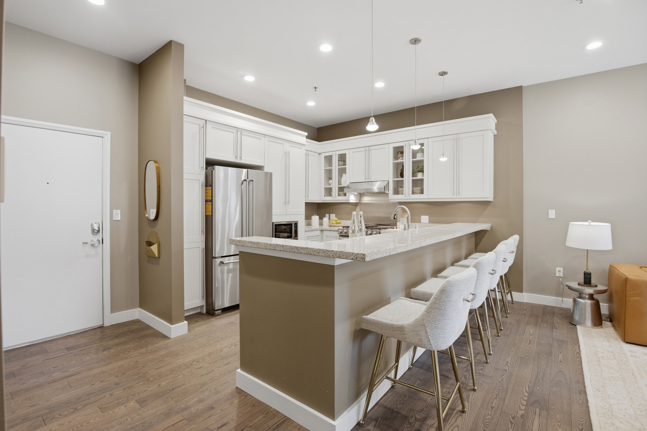 Contemporary kitchen featuring a breakfast bar with seating, white cabinetry, stainless steel appliances, and pendant lighting