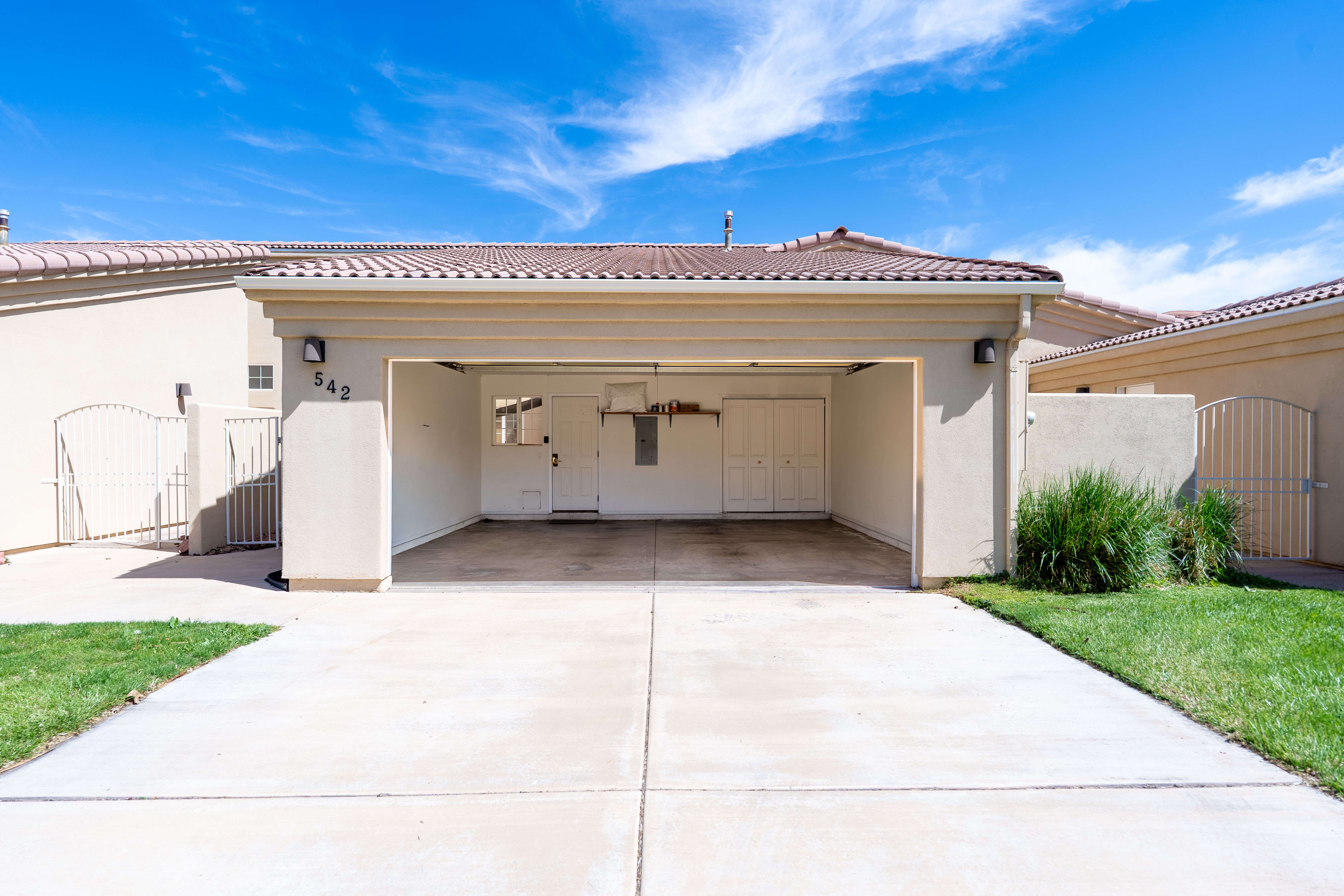 Open carport entrance featuring a concrete driveway, stucco exterior, and red tile roof