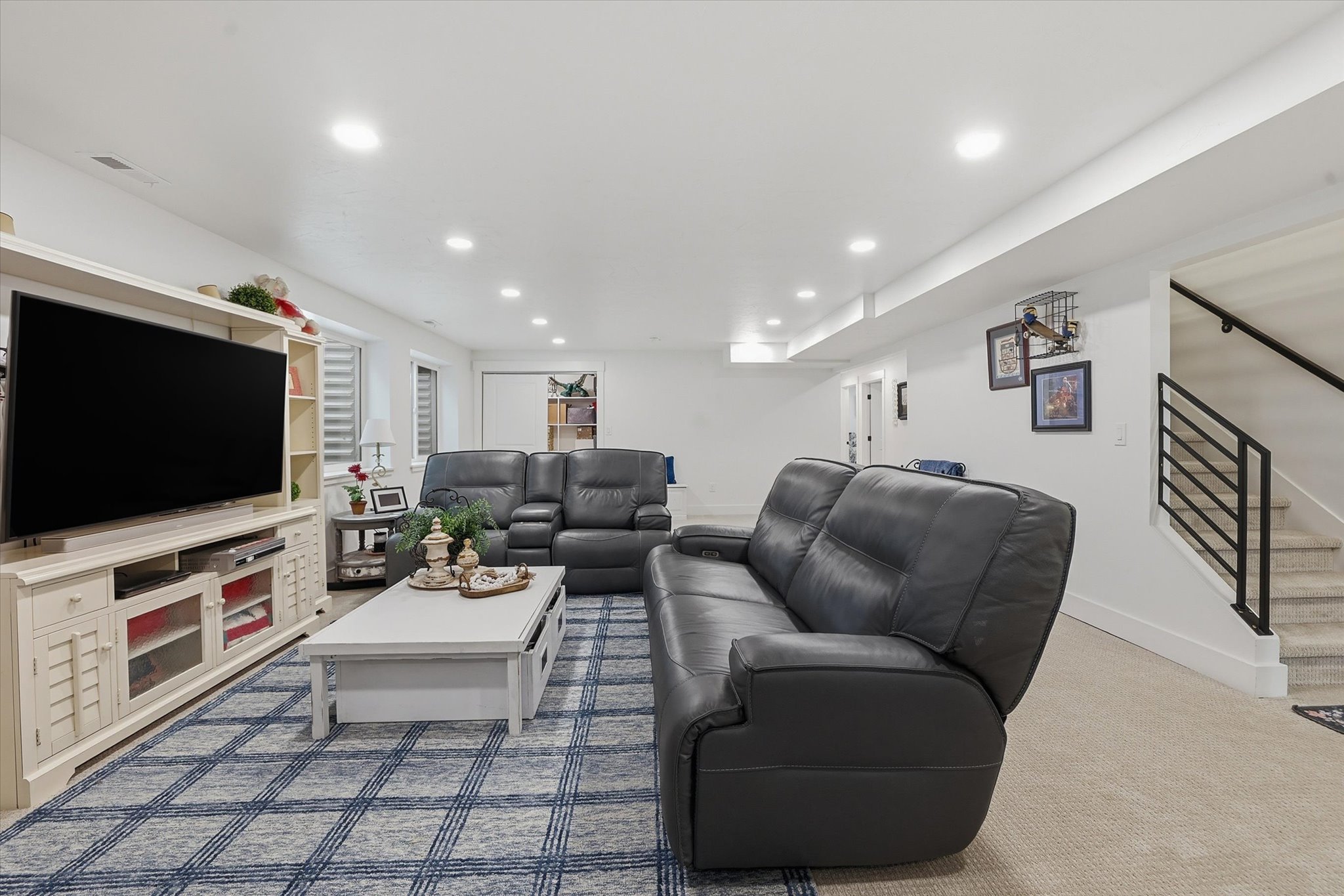 Finished lower-level living space featuring recessed lighting, light-toned carpeting, and a built-in media console with open shelving