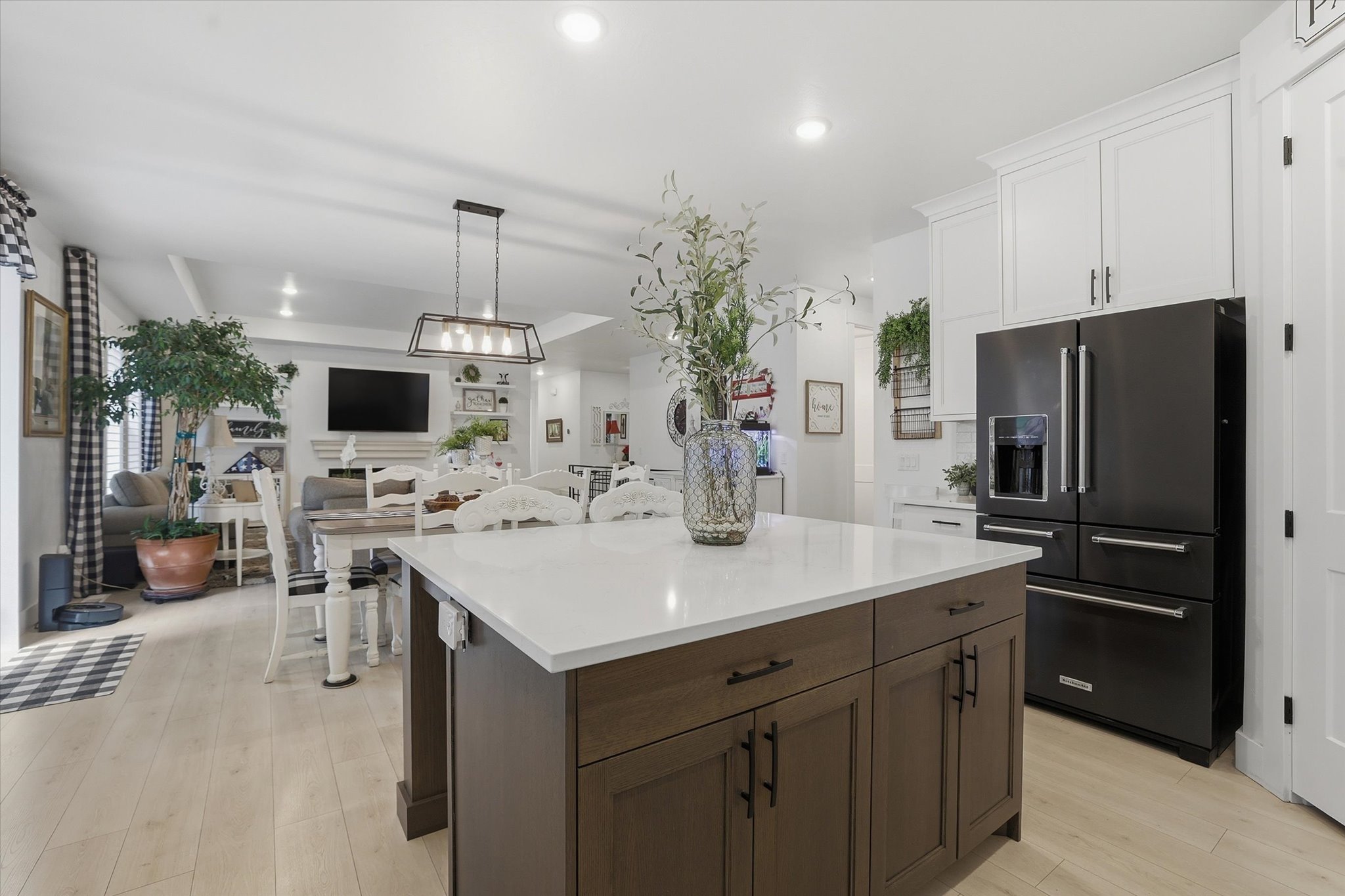 Kitchen featuring a dark wood-finish island with a white countertop and contrasting white cabinetry, a black French door refrigerator, and recessed lighting
