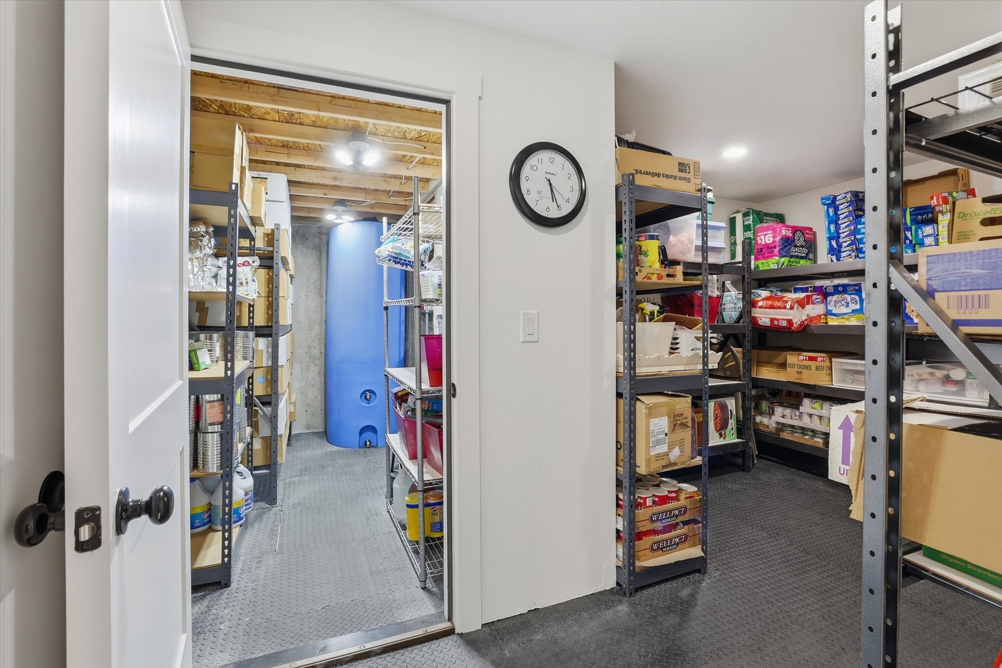 Organized storage area featuring industrial shelving, durable rubber flooring, and an exposed wood beam ceiling