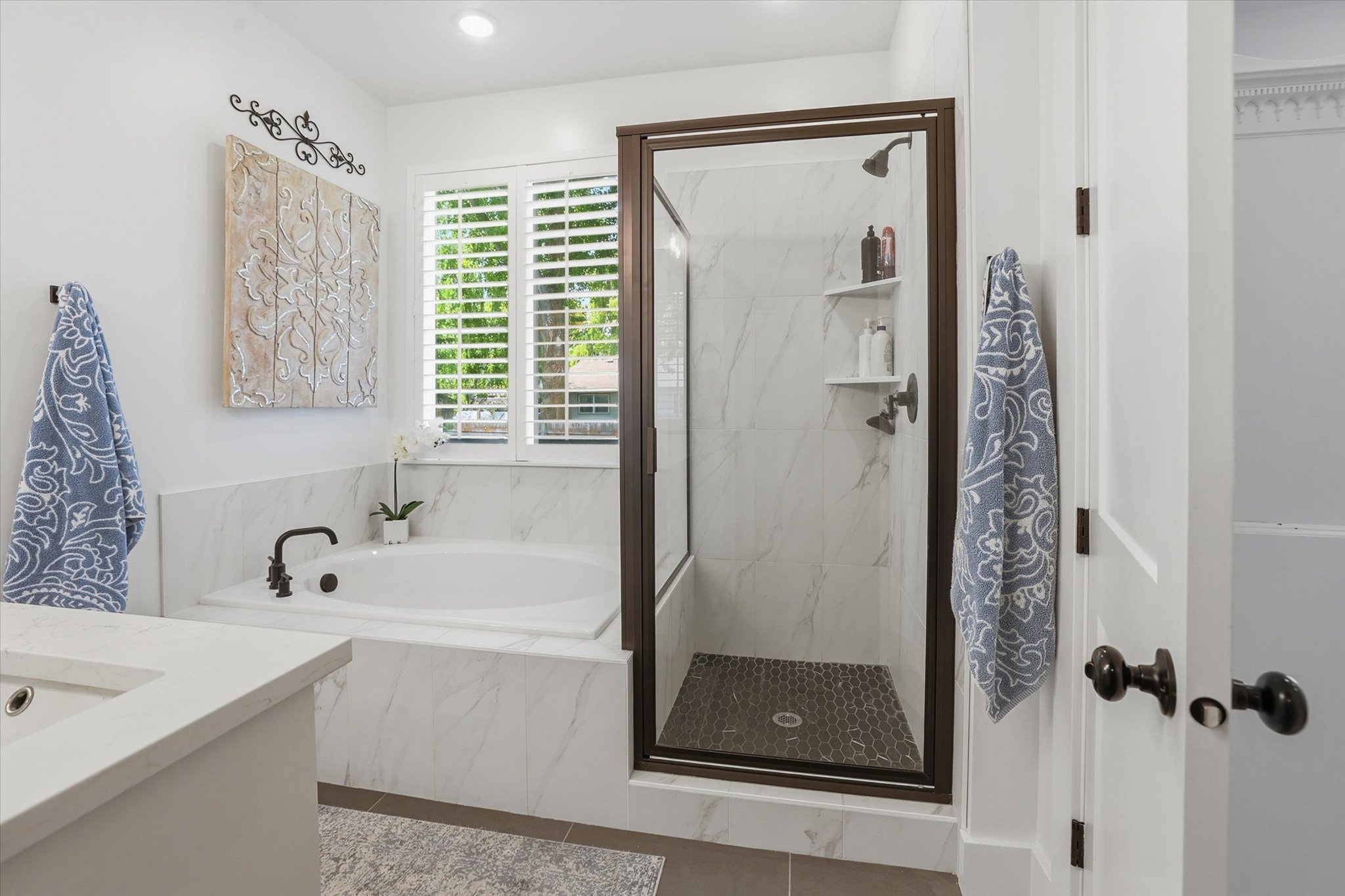 White marble-finish tile surrounds a built-in tub with a black faucet