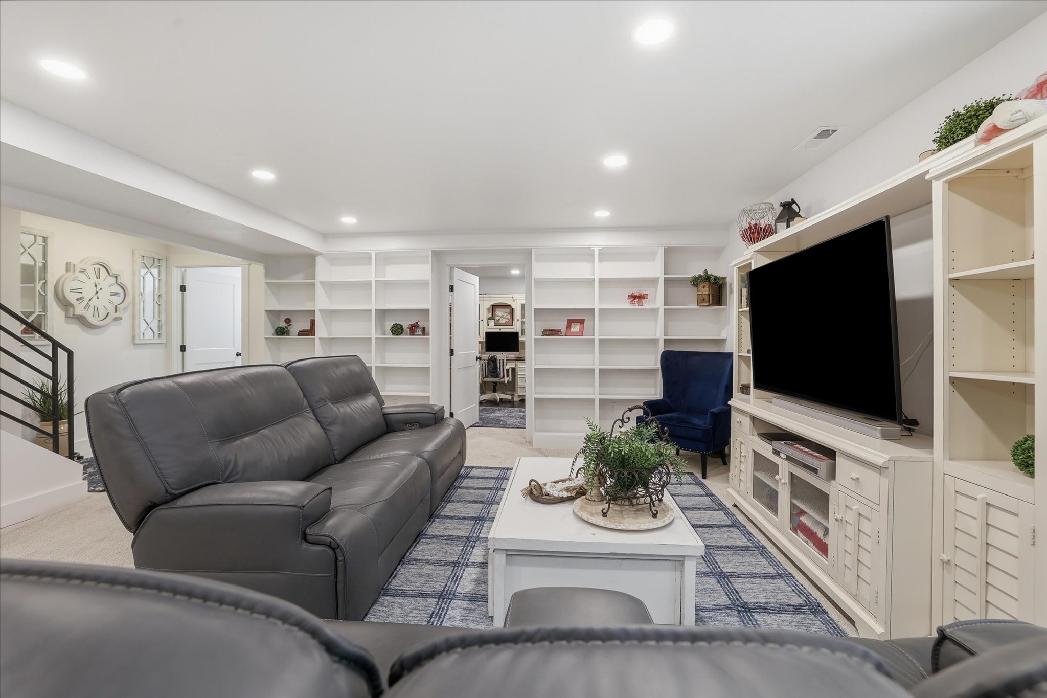 Spacious lower level featuring recessed lighting, extensive built-in shelving, white trim, and a contemporary staircase with black metal railing