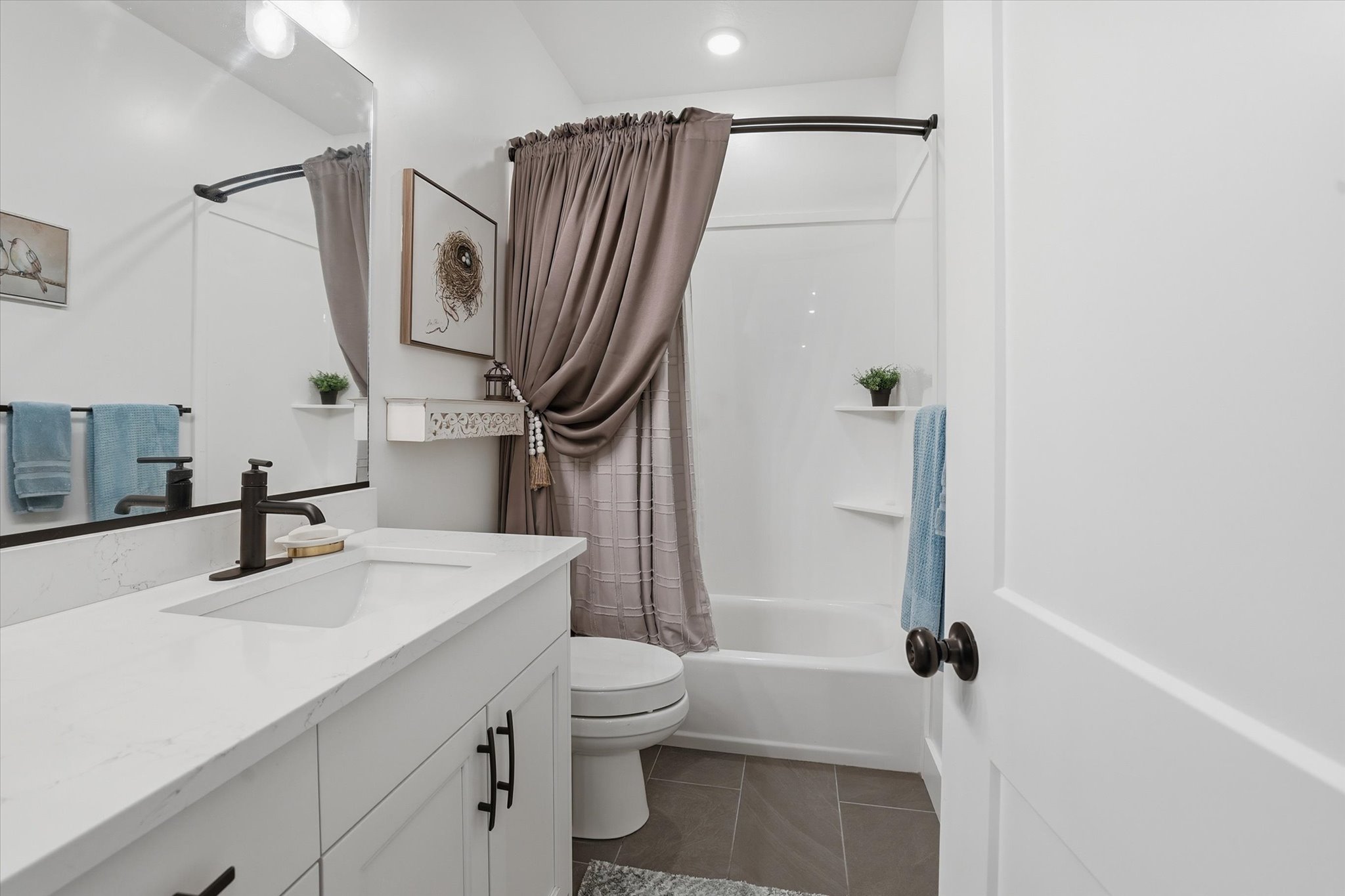 Bathroom featuring a white vanity with an integrated sink, dark bronze fixtures, and a spacious mirror