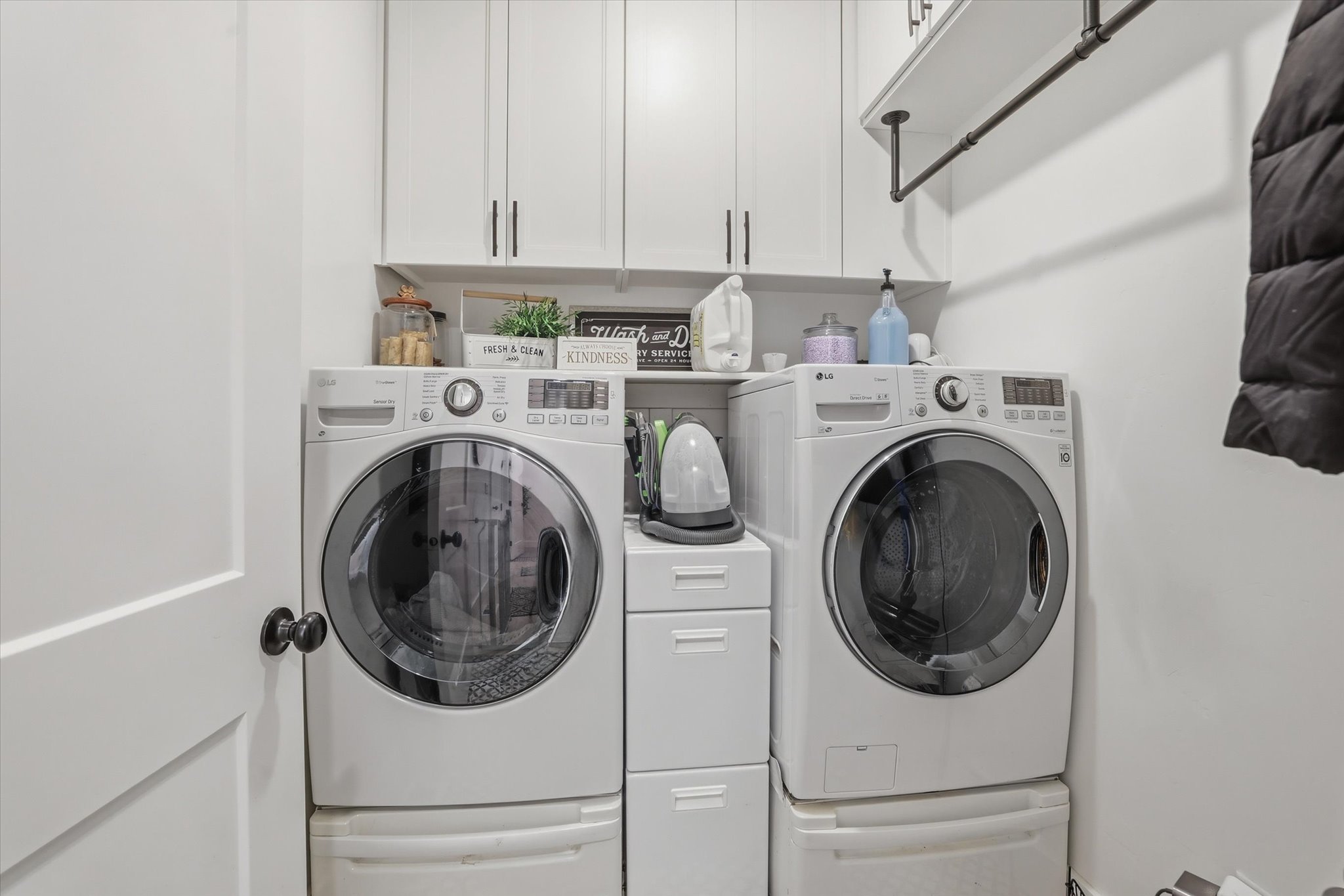 Laundry area featuring white cabinetry with black hardware, open shelving, and a hanging rod