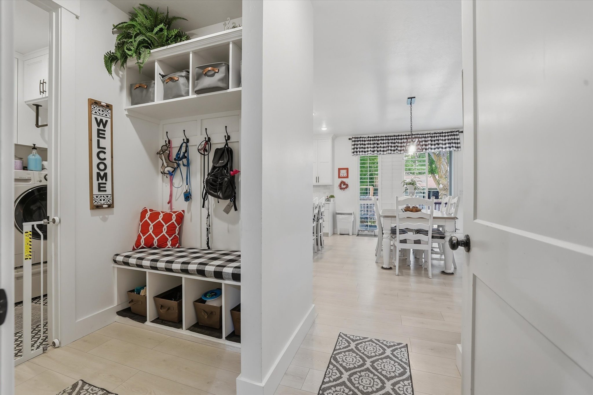 Entryway featuring a built-in mudroom bench with cubby storage and coat hooks, wood-finish flooring, and a laundry area with built-in cabinetry