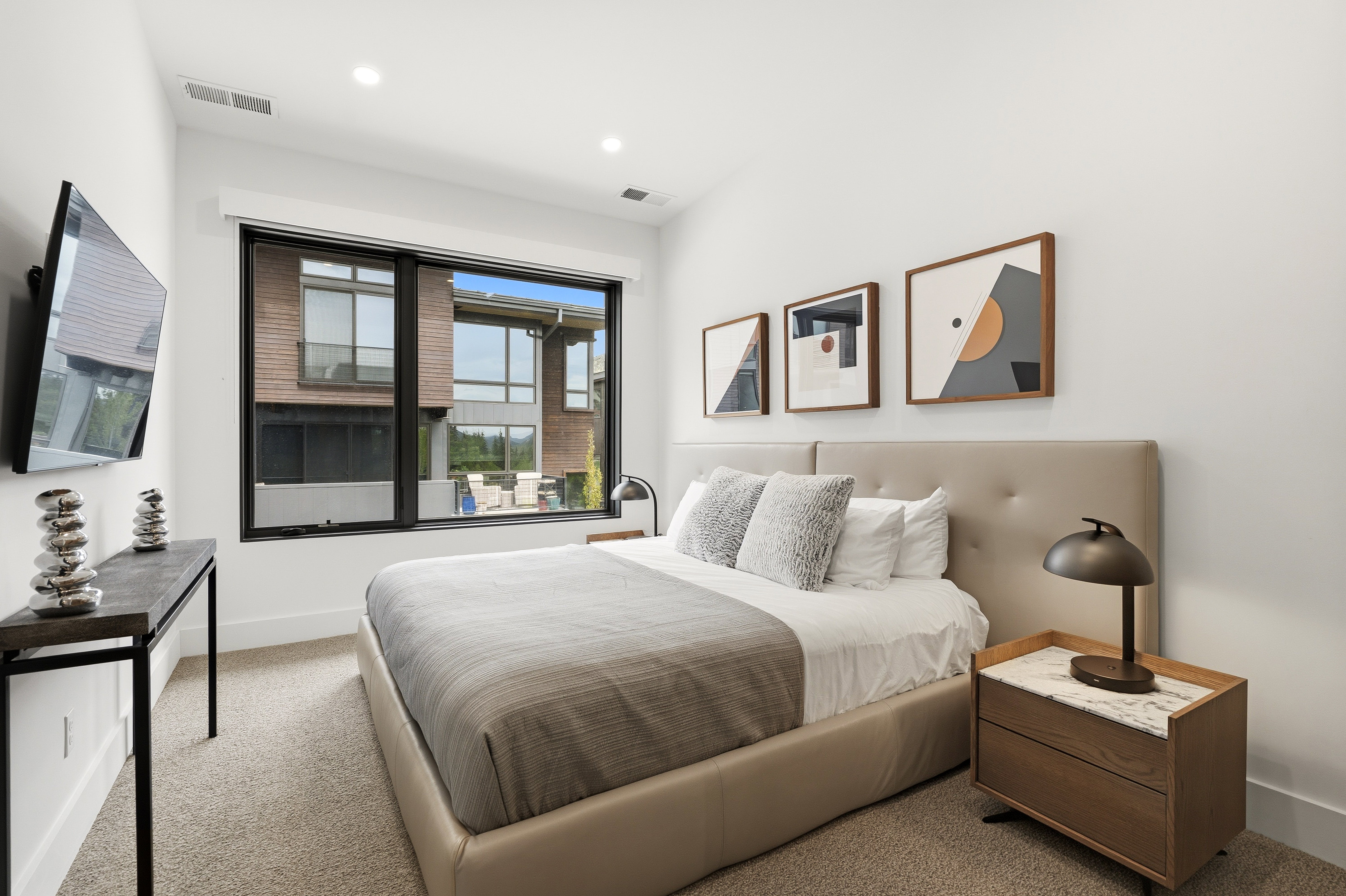 Contemporary bedroom featuring a large picture window, recessed lighting, and neutral wall paint