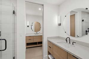 Contemporary bathroom featuring light wood-finish dual vanities with an integrated sink, matte black fixtures, and a large circular mirror