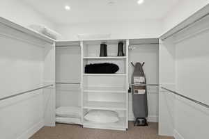 Walk-in closet featuring built-in shelving, multiple hanging rods, recessed lighting, and carpeting