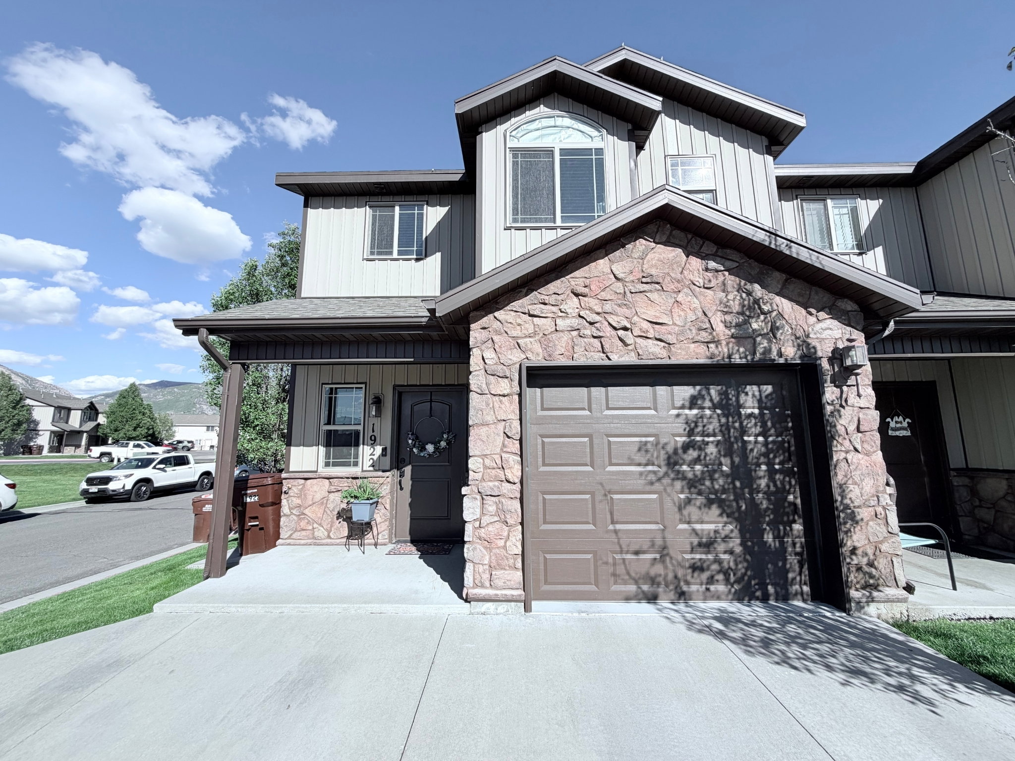 Two-story residence featuring a stone-clad facade, attached garage, and a covered porch entry