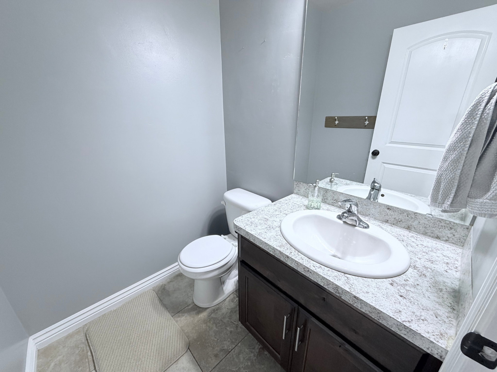 Half Bathroom on main level featuring a dark wood-finish vanity with an integrated white sink and a light countertop