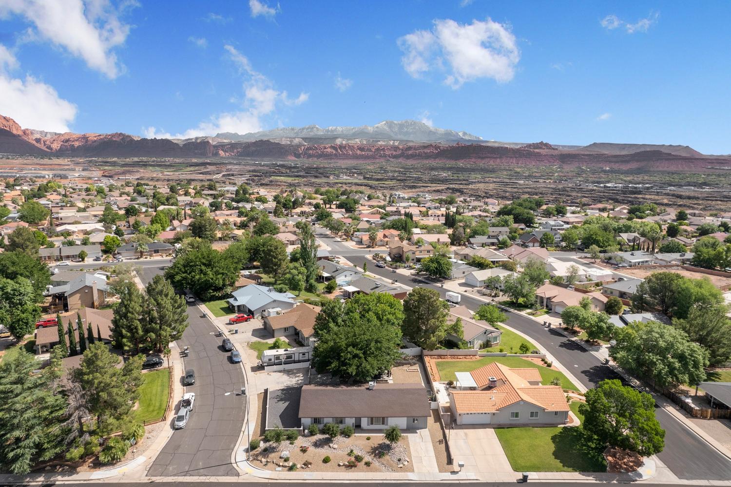 Expansive neighborhood with diverse residential architecture and mature trees, set against a backdrop of distant mountains