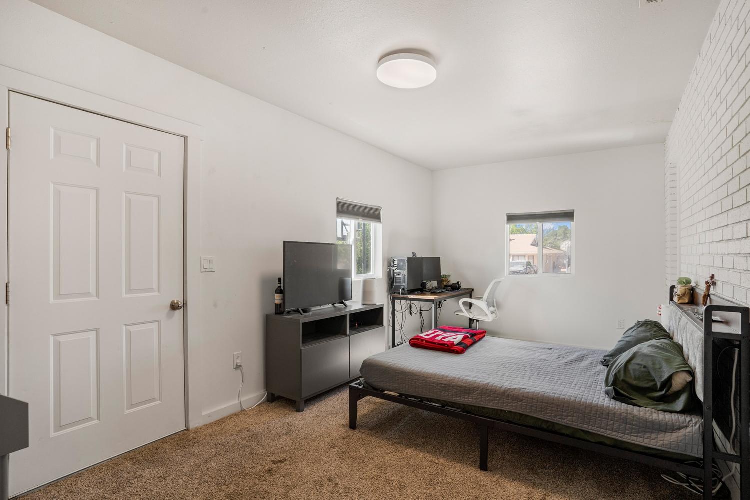 Spacious room featuring light-toned walls, a textured accent wall, and two windows providing natural light