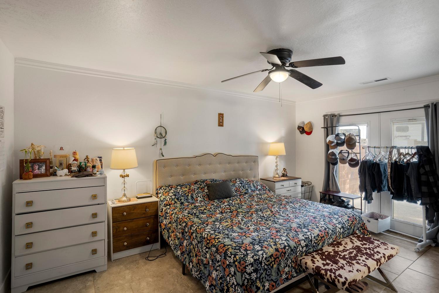 Spacious room featuring a tufted fabric headboard, crown molding, and a ceiling fan with integrated lighting