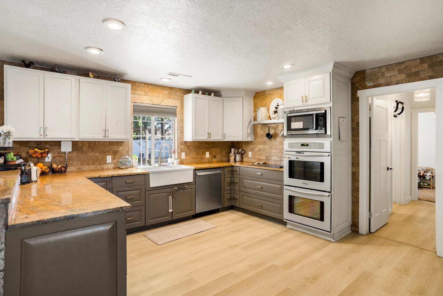 Kitchen featuring light wood-finish flooring, white upper cabinetry, and contrasting gray lower cabinetry