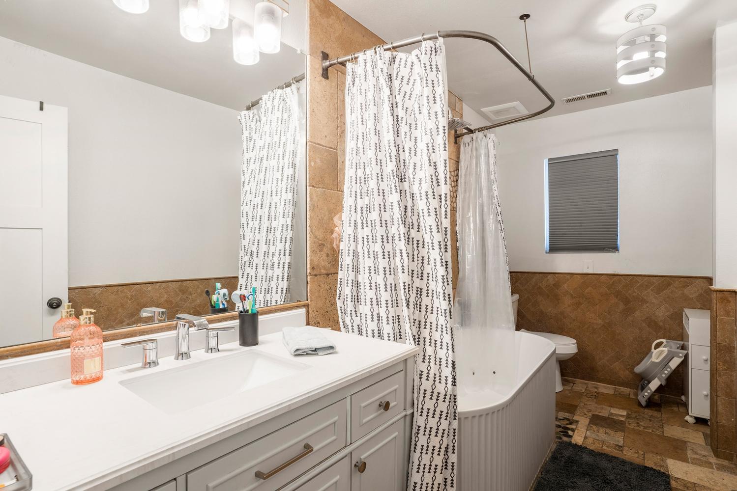 Bathroom featuring a vanity with an integrated sink, polished chrome faucet, and expansive mirror