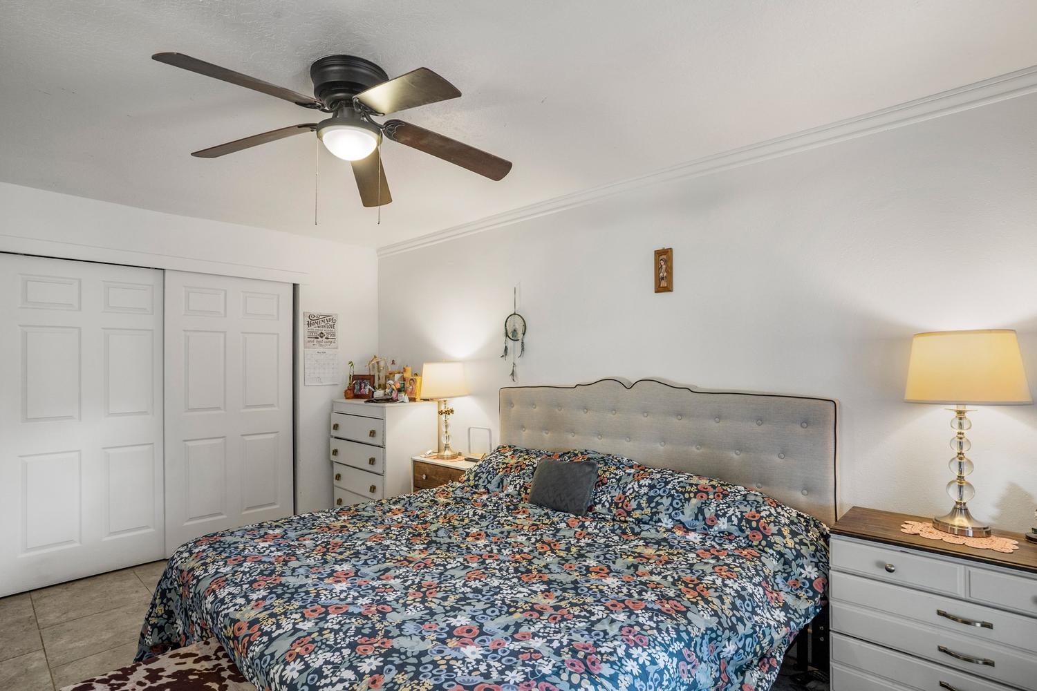 Bedroom with a ceiling fan, crown molding, and paneled bifold closet doors