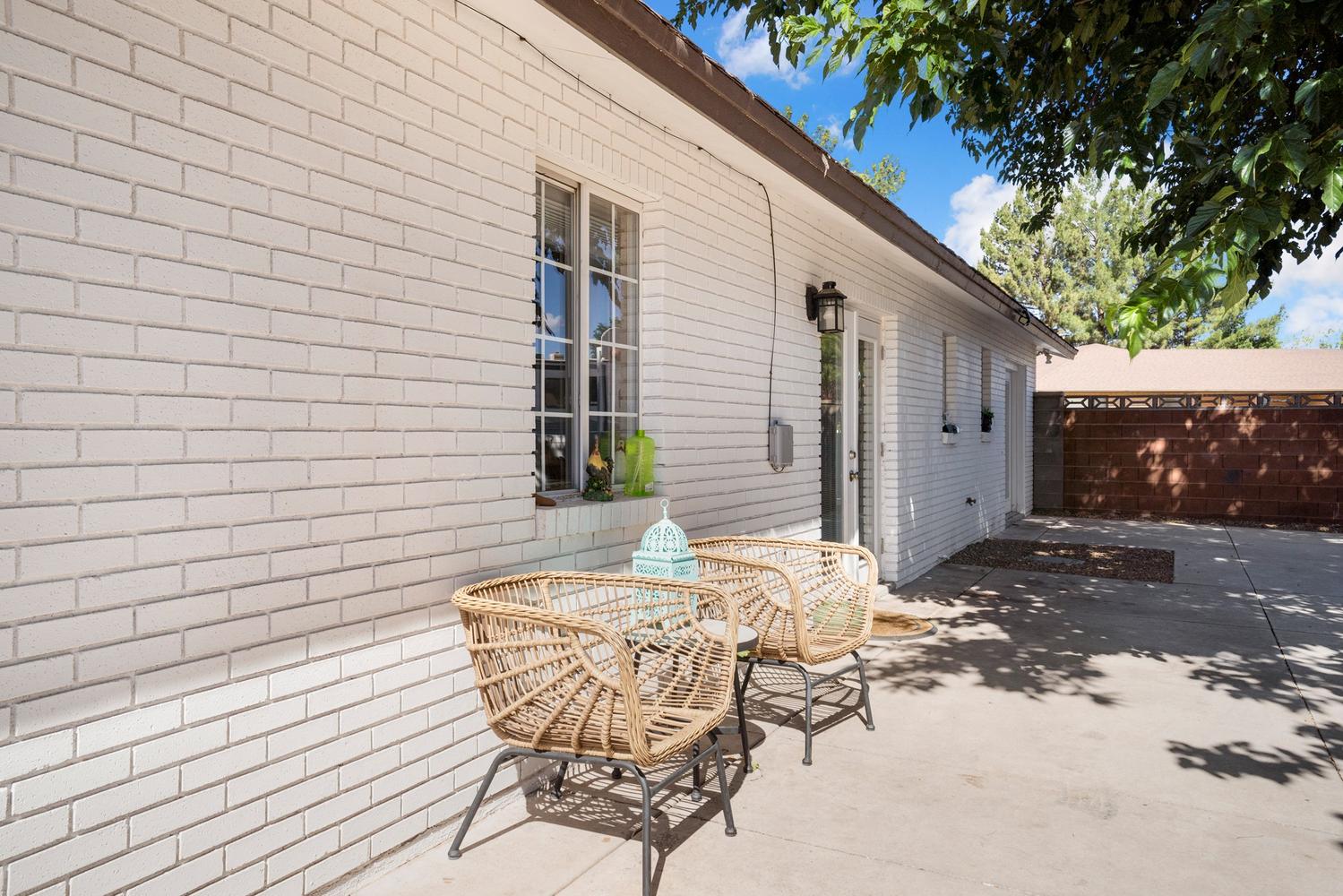 Patio space featuring a concrete surface, white painted brick exterior, exterior lighting fixture, and a glass paneled door
