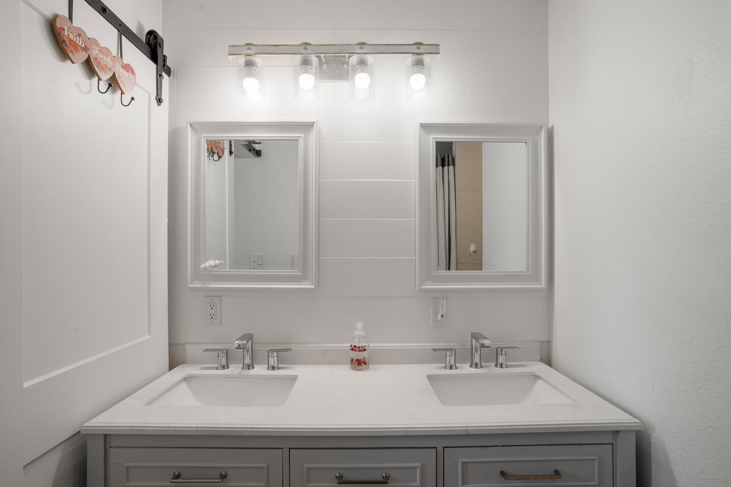 Dual vanity with white cabinetry, integrated sinks, chrome fixtures, and a light-toned countertop