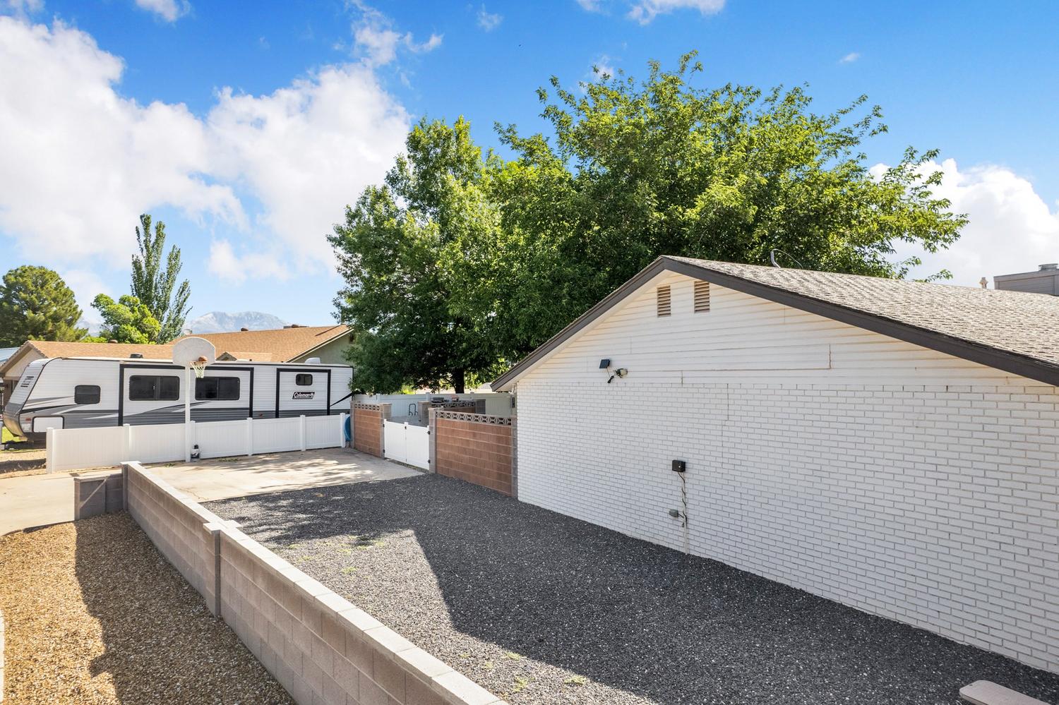 Expansive gravel-surfaced area providing ample space, bordered by a concrete block wall