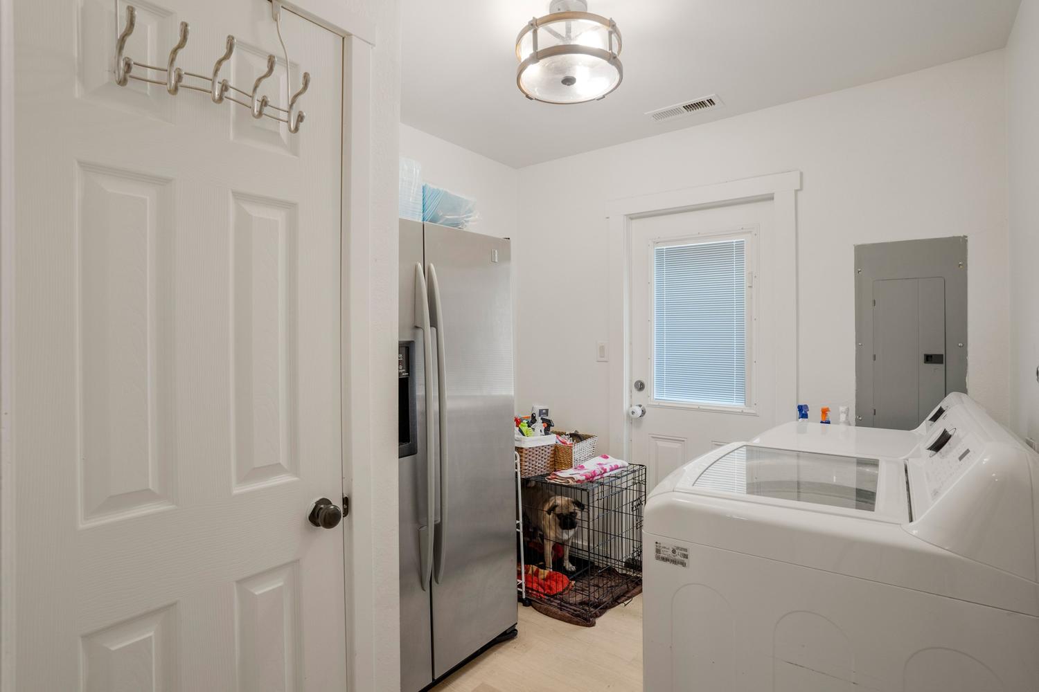 Utility space featuring a modern ceiling light fixture, white paneled door, and light wood-finish flooring