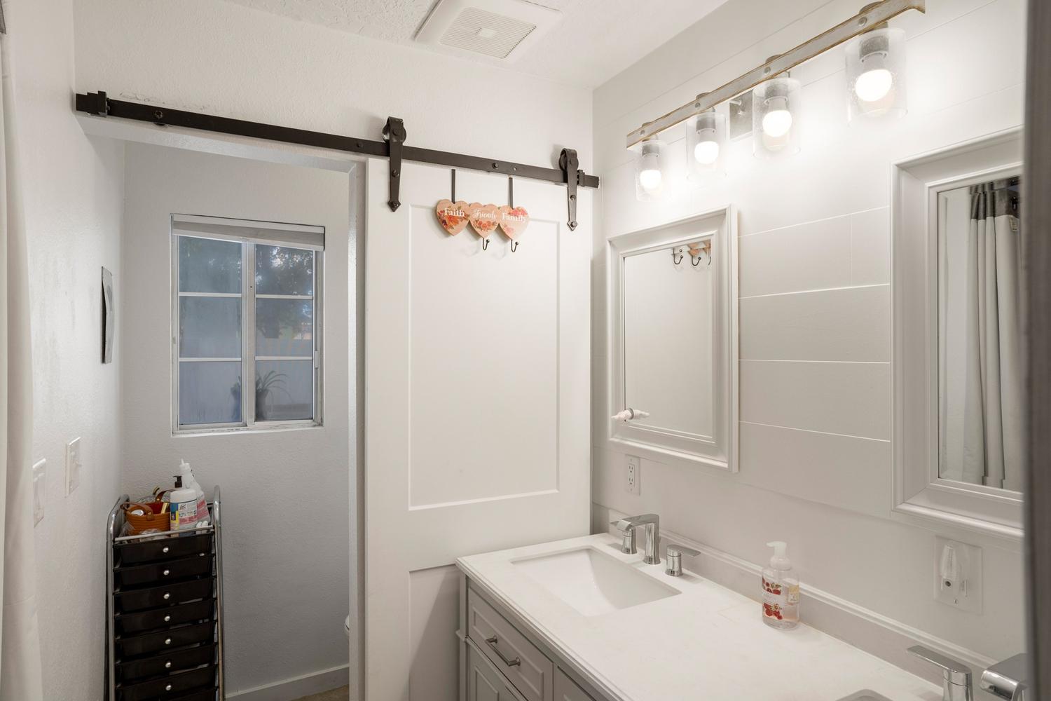 Bathroom vanity featuring a light-colored countertop with dual sinks, modern chrome faucets, and two framed mirrors