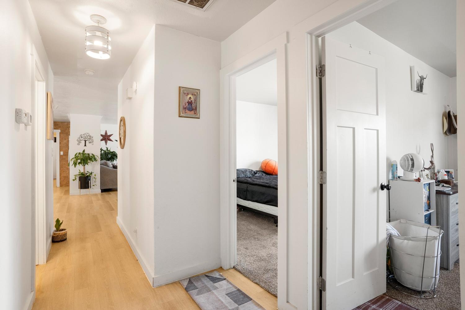 Open interior hallway featuring light wood-finish flooring, white walls, and a modern ceiling light fixture