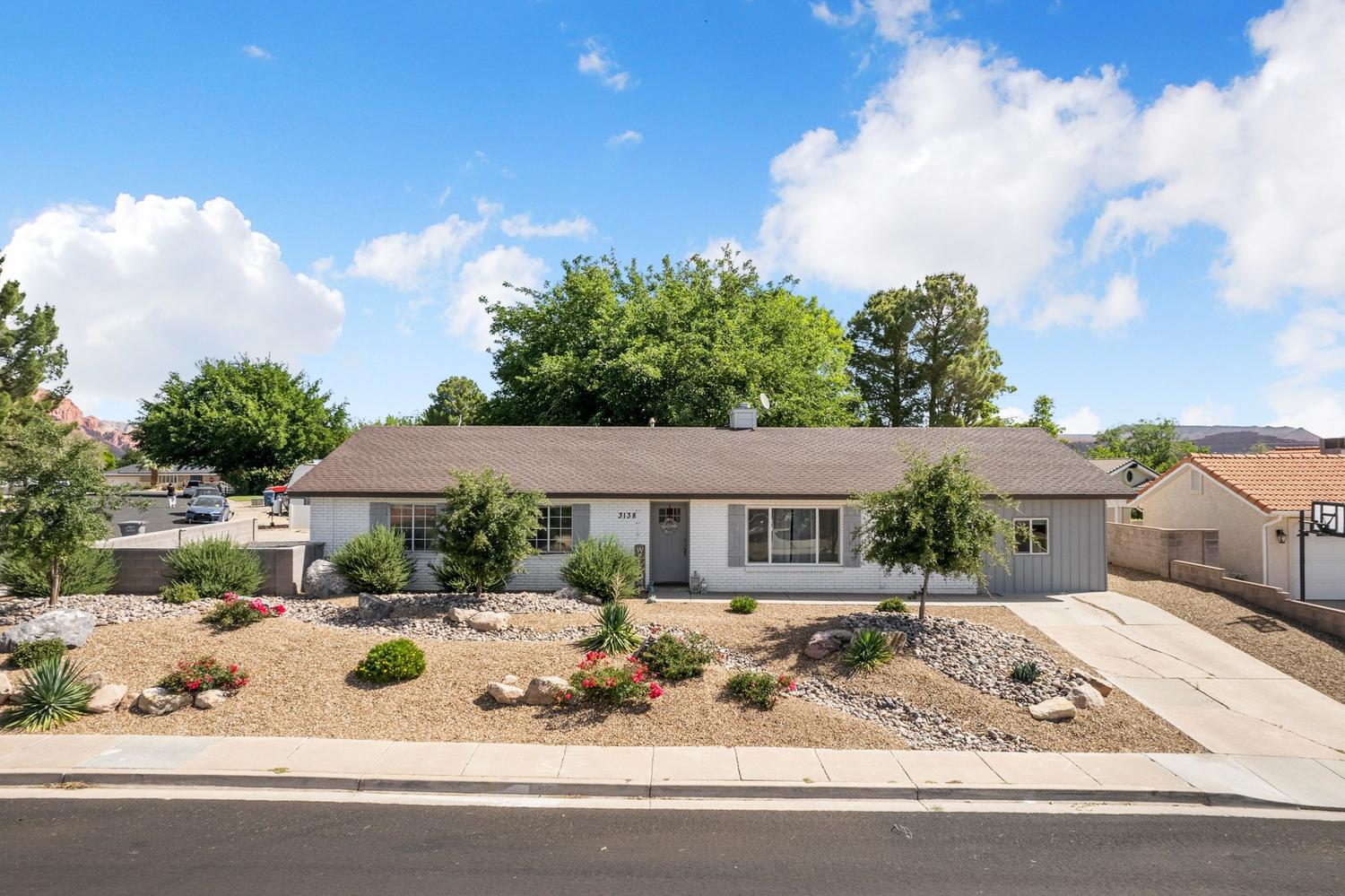 Single-story residence featuring a neutral exterior, a brown shingle roof, and a gravel and rock front yard