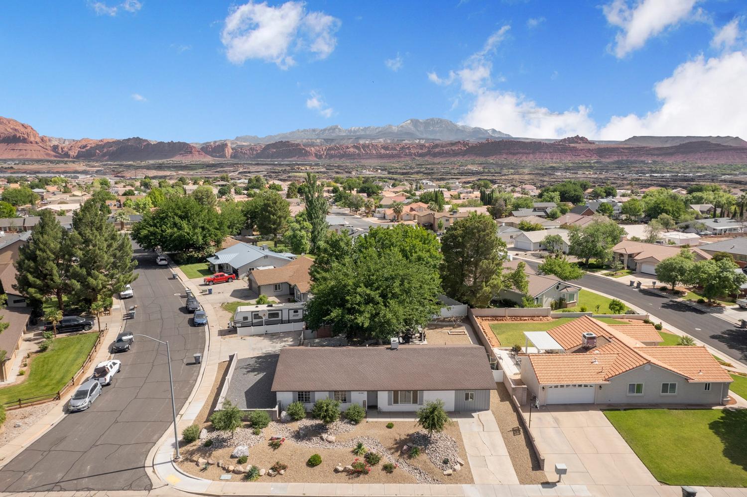 Residential neighborhood featuring a mix of mature trees and distant red rock mountains