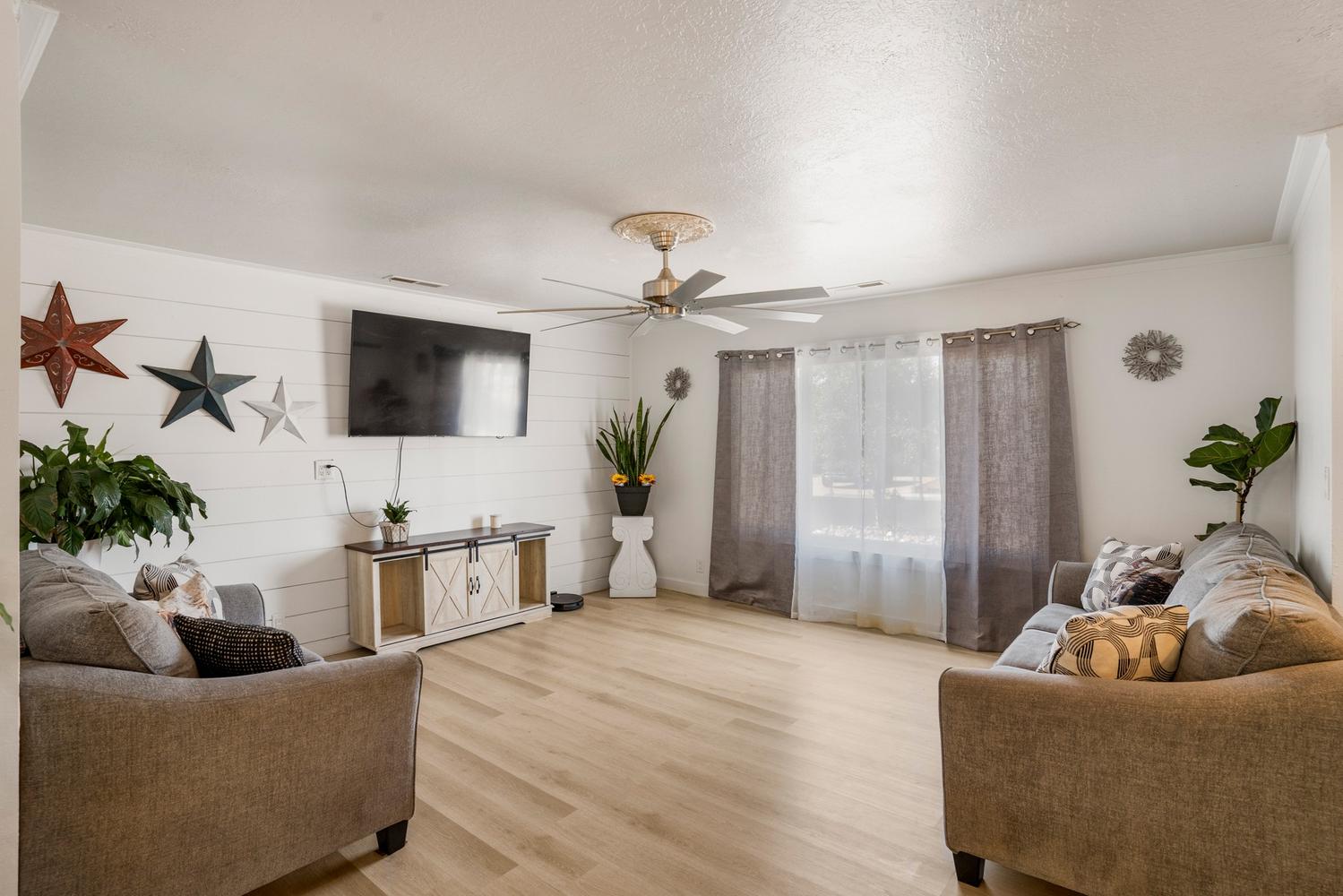 Spacious interior featuring light wood-finish flooring, a ceiling fan with decorative medallion, and white shiplap accent wall