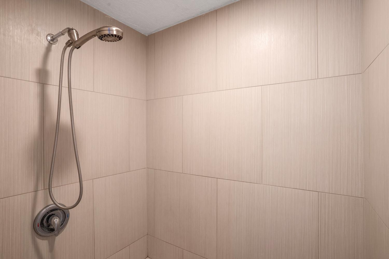 Shower stall featuring large format rectangular tiles with a subtle striated pattern
