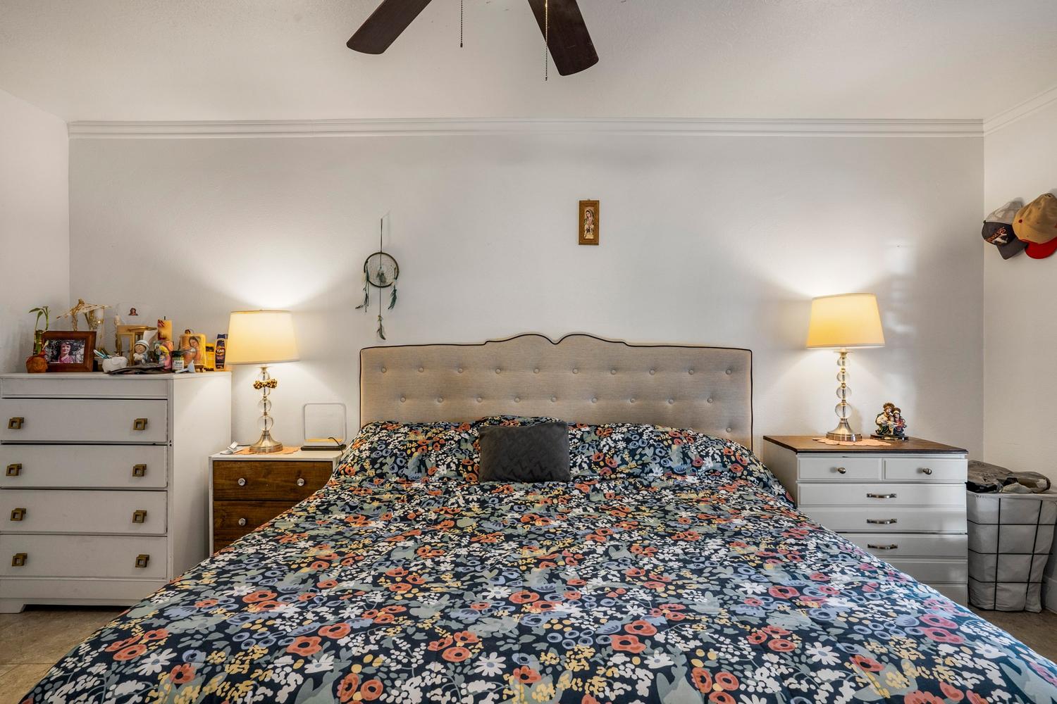 Spacious bedroom featuring an upholstered headboard, crown molding, and a ceiling fan